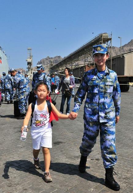 2015年3月，也门，海军女战士牵着一名小女孩的手准备登上军舰。